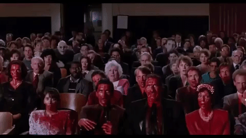 An animated GIF from The Addams Family showing a theater audience covered in blood gasping in horror, while Uncle Fester (Christopher Lloyd) sits in the back row grinning wildly.
