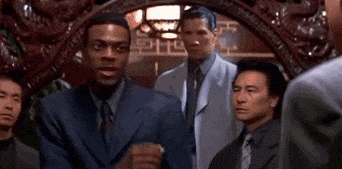 An animated GIF from Rush Hour showing LAPD Detective James Carter (Chris Tucker) breaking into an impromptu, energetic Michael Jackson dance move inside a Chinese restaurant while surrounded by unimpressed mobsters.