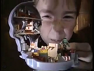 An animated GIF from a 90s Mighty Max TV ad showing a kid inspecting a micro skull playset crammed with Frankenstein-style monster figures.