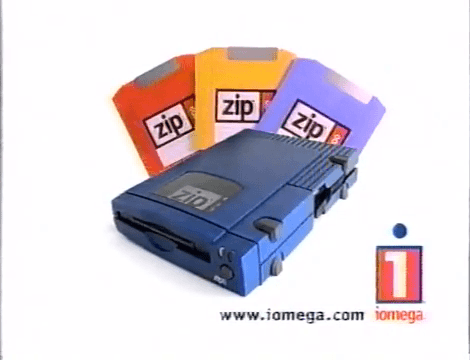90s Iomega TV ad showing a navy blue Zip 100 drive alongside a fan of colorful 100MB Zip floppy-replacement disks.