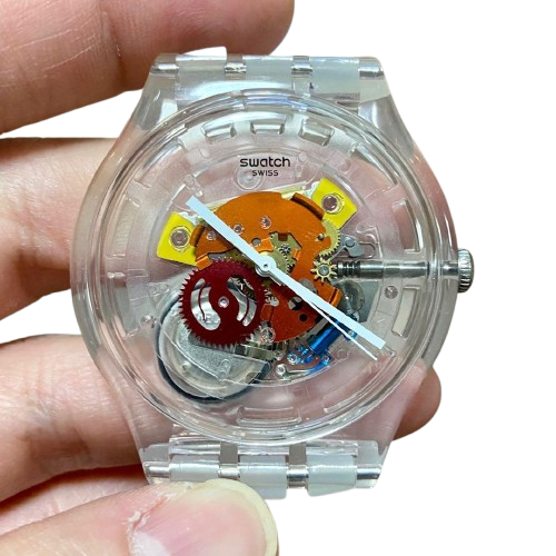 close-up of a vintage Swatch Jelly Fish wrist watch, featuring a completely transparent plastic case and strap that exposes its colorful orange and red internal gears.