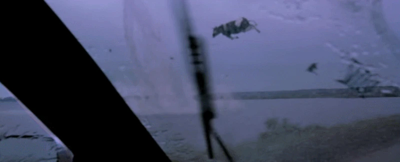 An animated GIF from Twister capturing a hilarious and chaotic moment through a truck windshield as a black-and-white Holstein cow gets swept up and hurled through the air by a massive tornado.