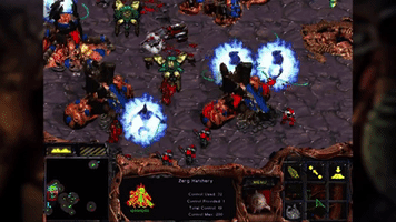 An animated GIF from original StarCraft showing Protoss High Templars unleashing massive blue Psionic Storms onto a Zerg Hatchery overrun by Zerglings.