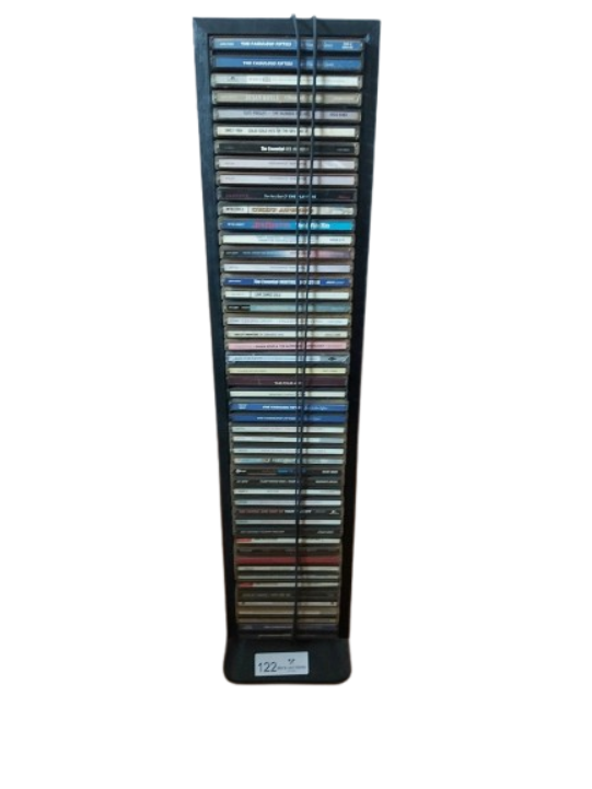 A vertical floor-standing black metal wire rack CD tower tightly packed with over 40 album jewel cases, showing the spine titles held in place by twin front tension cables.