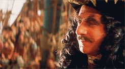 An animated GIF from Hook showing Captain Jas. Hook (Dustin Hoffman) sneering sinisterly in close-up, twirling his mustache aboard the Jolly Roger.