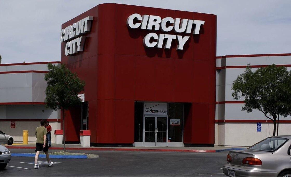 A shot of a freestanding Circuit City retail location, showcasing its iconic bold red storefront design shaped like a massive plug-in electronics box.
