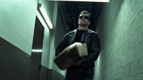 An animated GIF from Terminator 2: Judgment Day showing the T-800 (Arnold Schwarzenegger) clad in a leather jacket and sunglasses, coolly whipping out a hidden shotgun from inside a long cardboard rose box.