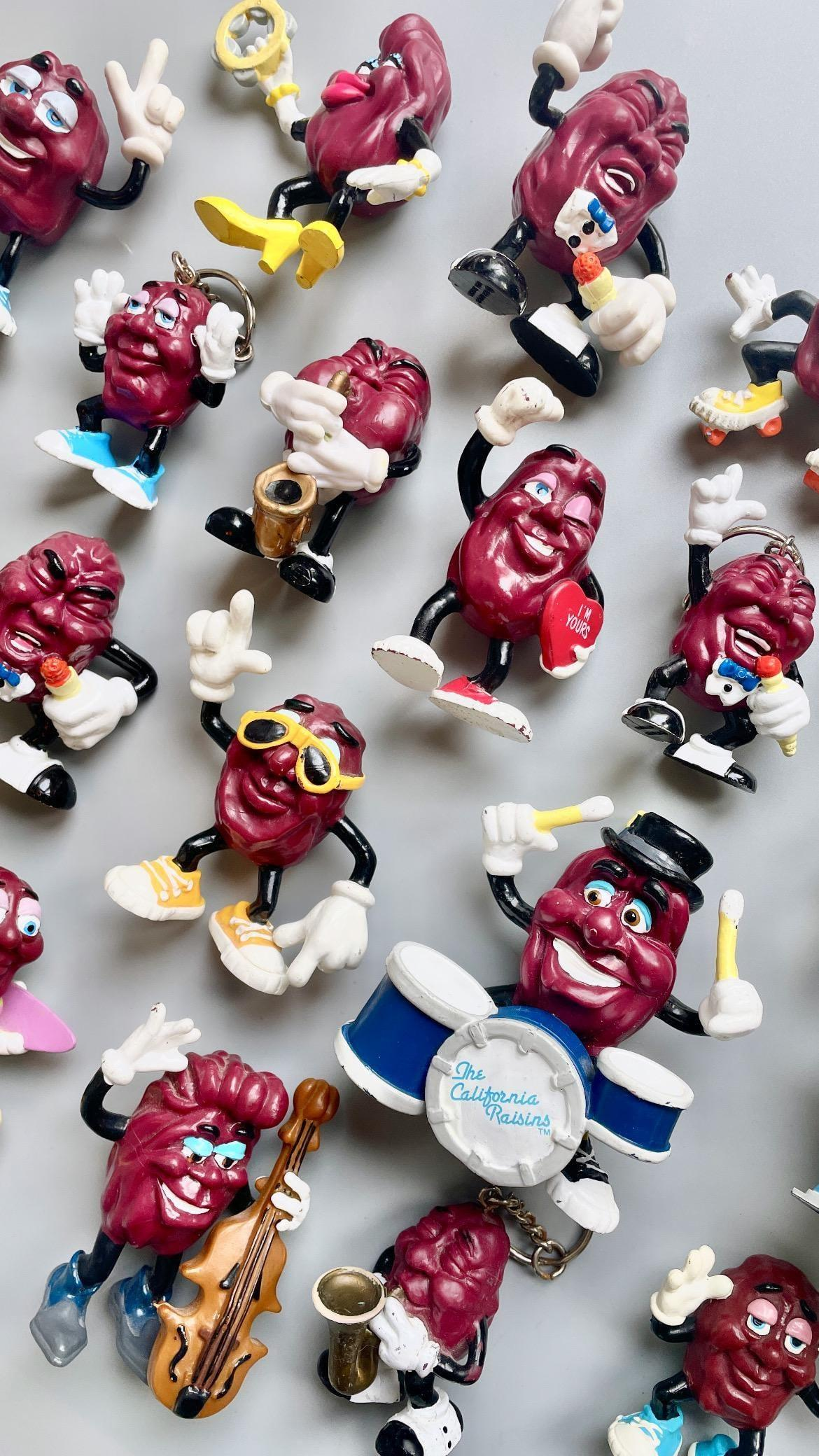 California Raisins PVC Figurine Collection Scrappy cluster of 1980s Post Cereal promotional California Raisins bendable vinyl figures jammed into a rock band lineup complete with sunglasses, bass, and drum kit.
