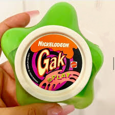 photograph showing a hand holding a star-shaped plastic container of neon green Nickelodeon Gak Splat slime.