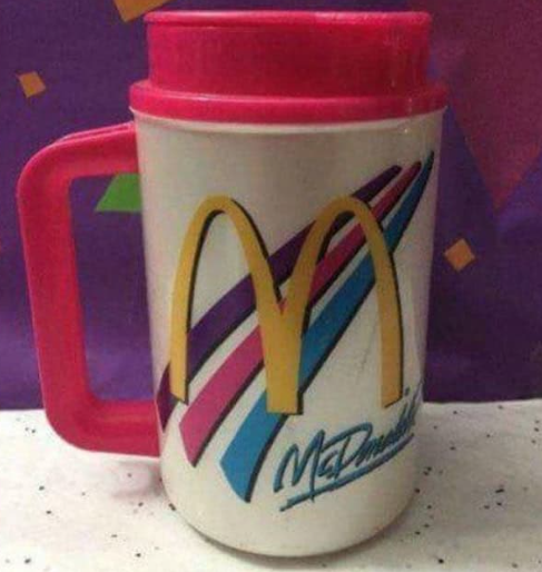 A white plastic 1990s McDonald's insulated refill mug featuring the iconic golden arches framed by bright teal and magenta brushstroke swooshes.