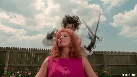 An animated GIF from Edward Scissorhands showing Edward (Johnny Depp) rapidly snipping his scissor blades around a suburban woman's head to give her a wild, avant-garde haircut.