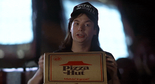 Wayne's World showing Wayne Campbell holding up a Pizza Hut box while deadpanning to the camera about refusing to bow to corporate sponsors.