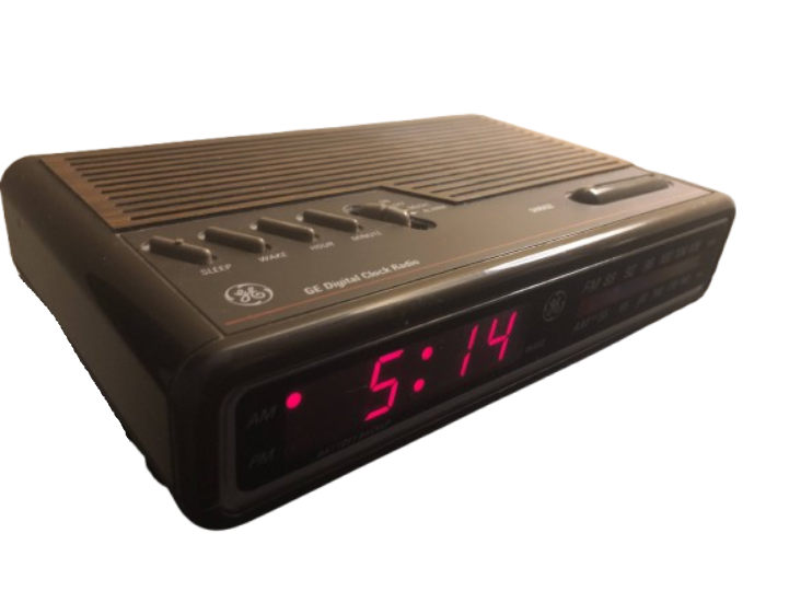 A classic General Electric digital clock radio featuring a faux-woodgrain top panel, physical alarm toggle switches, and a glowing red 4-digit LED display set to 5:14 AM.