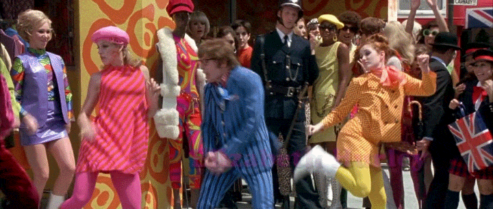 An animated GIF from Austin Powers: International Man of Mystery featuring Austin Powers (Mike Myers) doing a groovy, swinging-60s dance routine alongside retro mod dancers in bright suits and gogo boots on Carnaby Street.