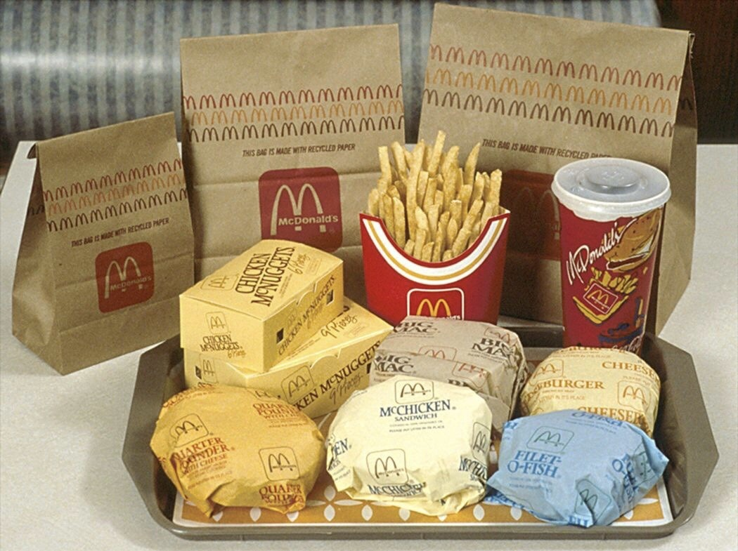 Vintage 1990s McDonald's Fast Food Tray Complete 90s McDonald's meal spread on a plastic tray, featuring paper-wrapped cheeseburgers, Filet-O-Fish, cardboard Chicken McNugget boxes, super-sized fries, and branded brown paper bags.
