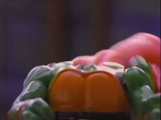 An animated GIF from a 90s TMNT toy commercial showing hands pressing down on a turtle action figure's chest to trigger its secret pop-up head mechanism.