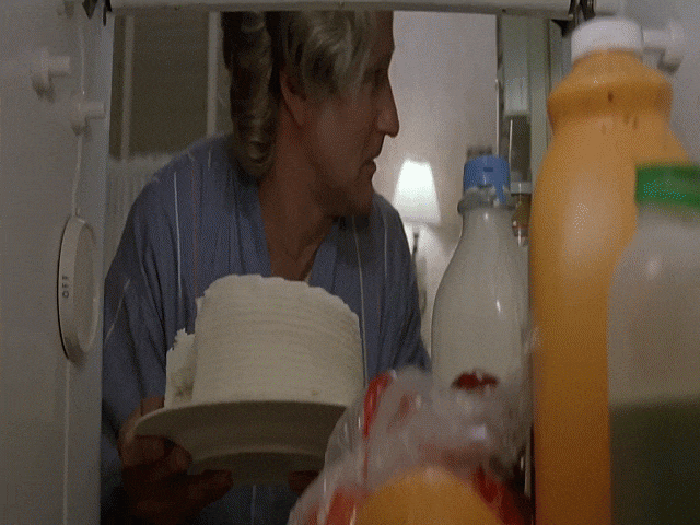An animated GIF from Mrs. Doubtfire showing Daniel Hillard disguised as Mrs. Doubtfire (Robin Williams) opening a hot oven door, accidentally setting her fake foam breasts on fire, and frantically swatting at the flames with pot holders.
