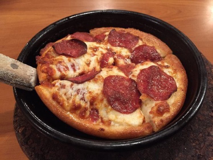 A piping-hot, golden-brown pepperoni Personal Pan Pizza served straight out of the oven inside its signature heavy black cast-iron skillet.