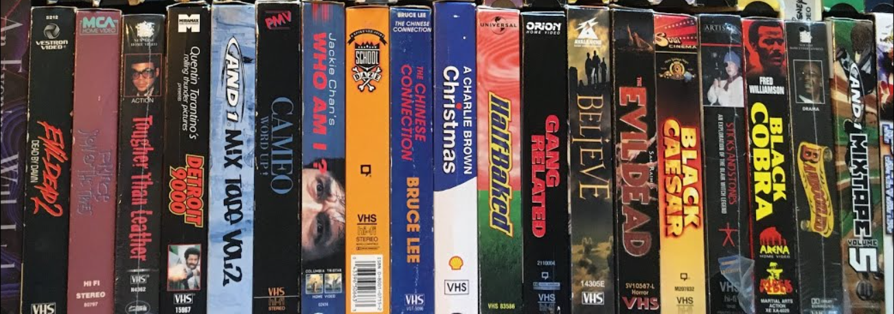 A vertical stack of vintage VHS tape spines featuring urban classics, kung fu, and cult films including AND1 Mixtape Vol. 5, The Evil Dead, Half Baked, Jackie Chan's Who Am I?, and Evil Dead 2.