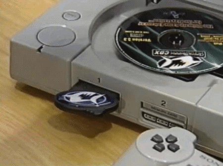 An animated GIF showing a GameShark CDX disc loaded inside an original grey PlayStation console alongside its matching memory card slot dongle, ready to unlock infinite health and secret cheat codes.