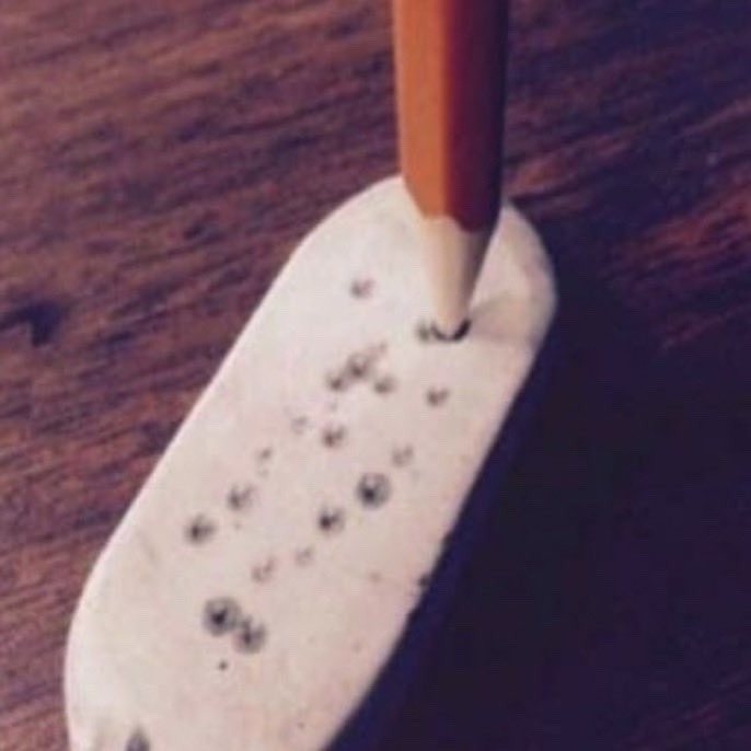 Pencil-Punctured Pink Pearl Eraser Classic bevel-edged Pink Pearl eraser severely wounded by dozens of graphite pencil stabs, the ultimate artifact of middle school test-taking boredom.