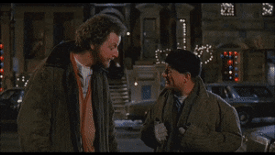 An animated GIF from Home Alone 2: Lost in New York showing the Wet/Sticky Bandits, Marv (Daniel Stern) and Harry (Joe Pesci), smirking and exchange high-fives on a dark New York street.